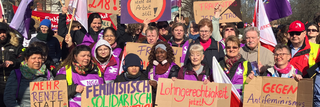 Ein Gruppenbild von Frauen beim 8. März mit Schildern. 